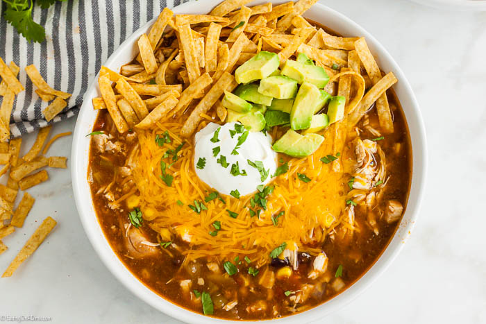 Bowl of Chicken Enchilada Soup topped with sour cream and tortilla strips. 