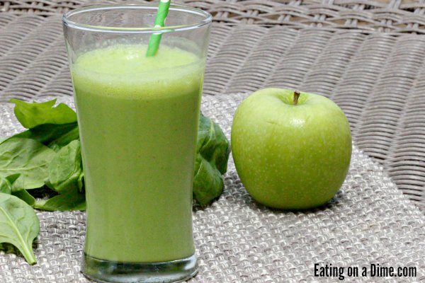 Apple and Spinach Green Smoothie in a clear cup with a green straw in it on a grey place mat. 