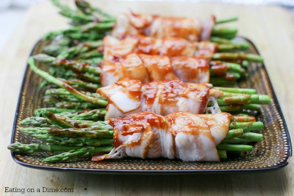 Bacon Wrapped Asparagus on a plate basted with BBQ Sauce on a platter