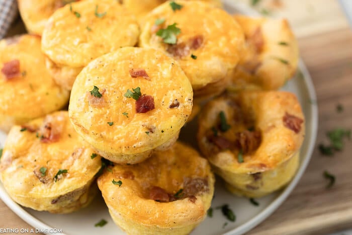 Lots of egg muffins stacked on a white plate 