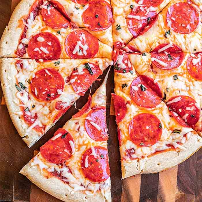 Close-up of a pepperoni pizza cut into slices with 1 slice slightly pulled away.  