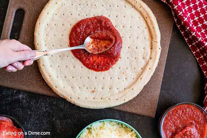 Spreading the sauce on the pizza crust