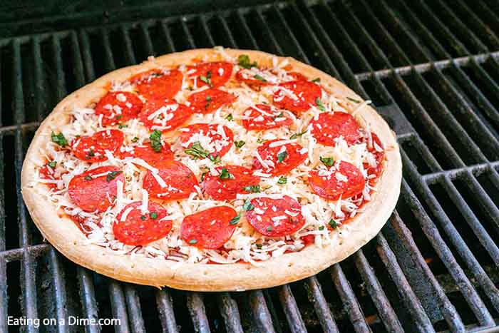 Learn how to grill pizza on a gas grill in literally 15 minutes. This quick and easy grilled pizza recipe is perfect for weeknight dinners and so easy and delicious. You won’t believe how easy it is to grill pizza with a premade crust. You are going to love this grilled pizza recipes! #eatingonadime #grilledpizza #easypizzarecipes