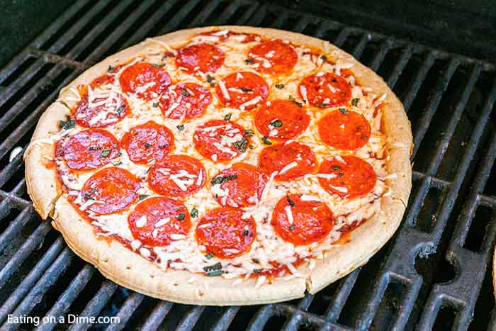 Learn how to grill pizza on a gas grill in literally 15 minutes. This quick and easy grilled pizza recipe is perfect for weeknight dinners and so easy and delicious. You won’t believe how easy it is to grill pizza with a premade crust. You are going to love this grilled pizza recipes! #eatingonadime #grilledpizza #easypizzarecipes