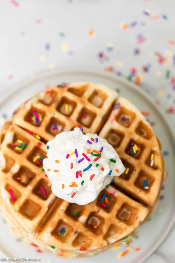 This cake mix waffles recipe is so fun and easy for the kids to make. These cake mix waffles boxes recipe can be made with your favorite flavors: funfetti, chocolate and strawberry. Learn how to make this cake mix waffles recipe with a box cake mix. This recipe is so easy, your kids can make this recipe boxes of cake mix waffles! #eatingonadime #cakemixrecipes #cakemixwaffles #easydesserts #kidrecipes Cake Mix Waffles topped with sprinkles and whipped cream