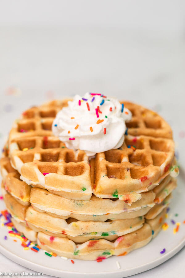 Cake Mix Waffles Stacked on a plate topped with whipped cream and sprinkles