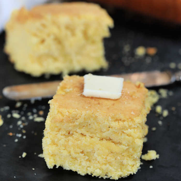 Close up image of cornbread with butter on top. 