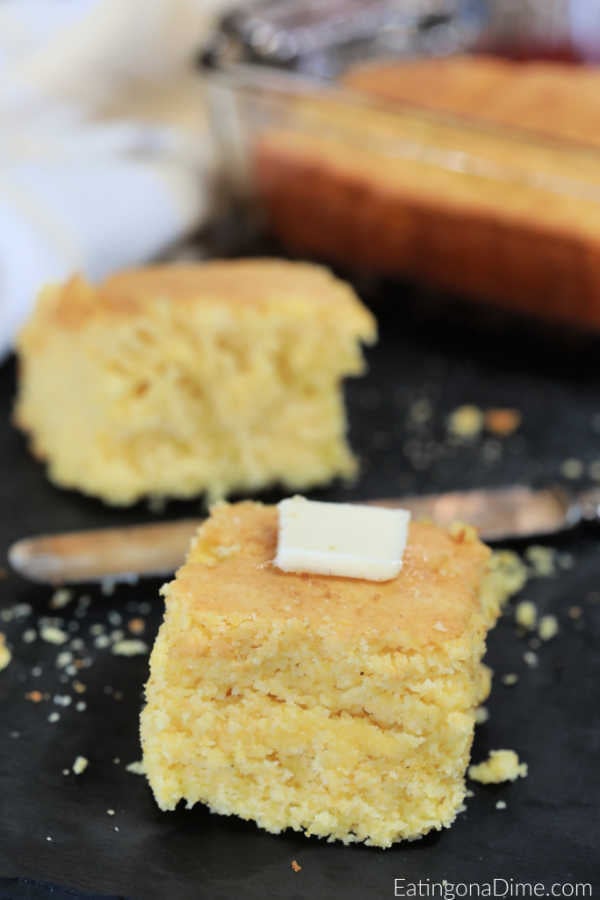 Close up image of a piece of cornbread with butter on a platter. 