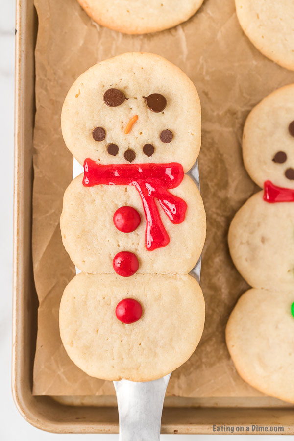Close up image of a snowman sugar cookie decorated on a cookie sheet.