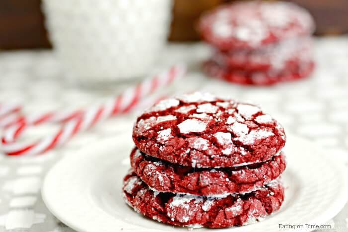 Close up image of 3 Red Velvet Cookies stacked on a plate with a candy cane in the background. 