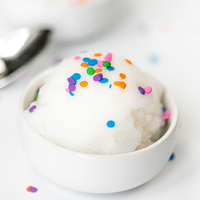 Close up image of snow ice cream in a white bowl with sprinkles on top. 