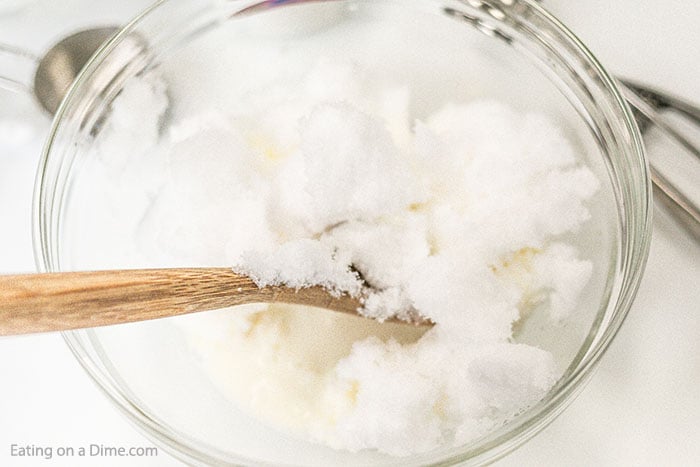 It is so easy to make this delicious and tasty Snow Ice Cream Recipe. Kids go crazy over this simple treat and it is a blast to make. Close up image of snow ice cream being mixed in a clear bowl with a wooden spoon.