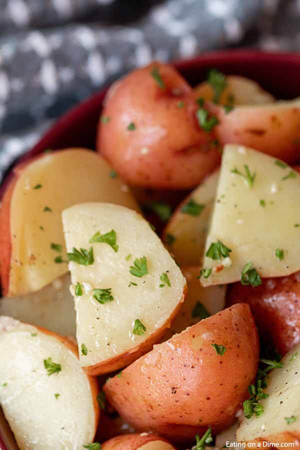 Cooked instant pot red potatoes in a large red bowl topped with fresh parsley.  