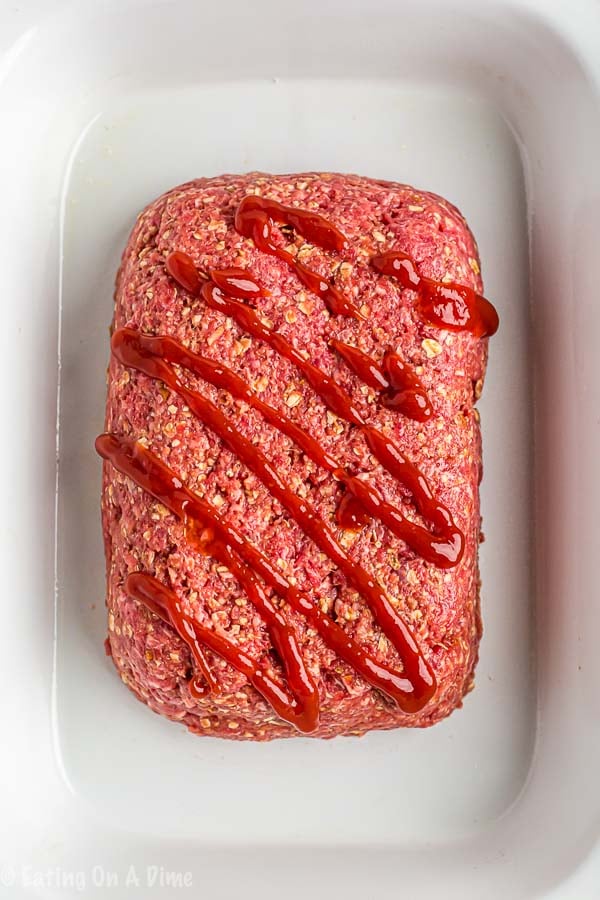 Shaping meatloaf into a loaf and topping with ketchup in a slow cooker