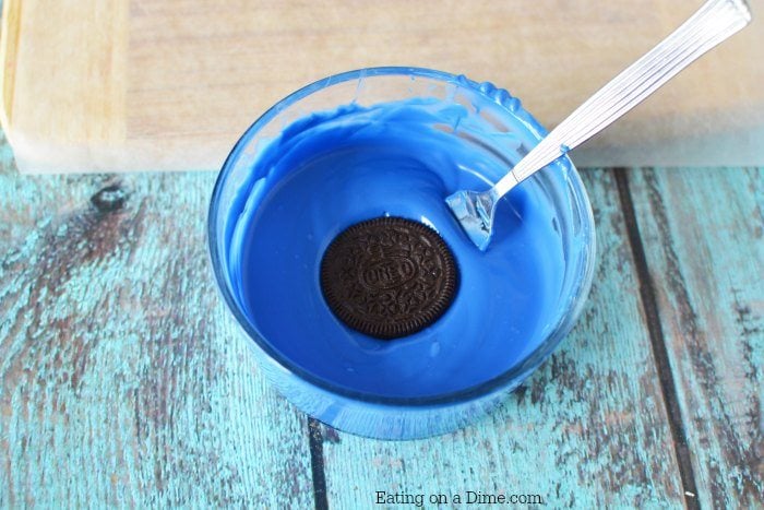 Melted blue chocolate with oreo being dipped in with a fork. 