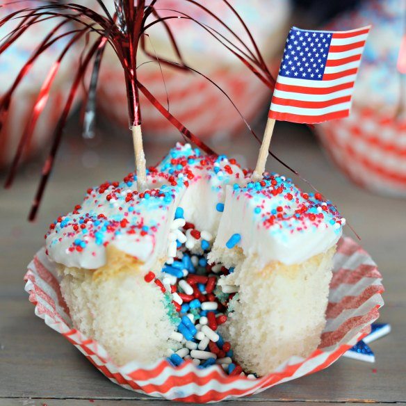 Cupcakes topped with red white and blue sprinkles and a American flag
