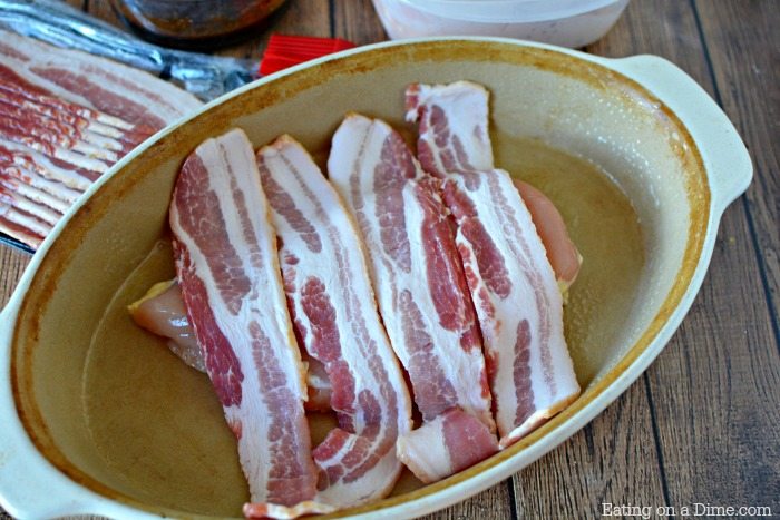 close up image of chicken with bacon on top in a baking dish. 
