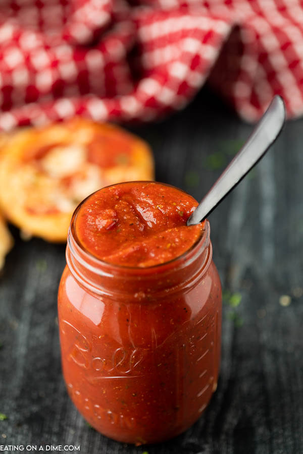 Pizza sauce in a mason jar with a silver spoon in it. 