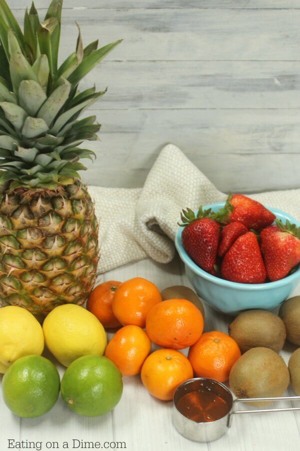 Ingredients needed for fruit salad - pineapple chunks, strawberries, cantaloupe, kiwis, mandarin oranges, limes, lemons, honey
