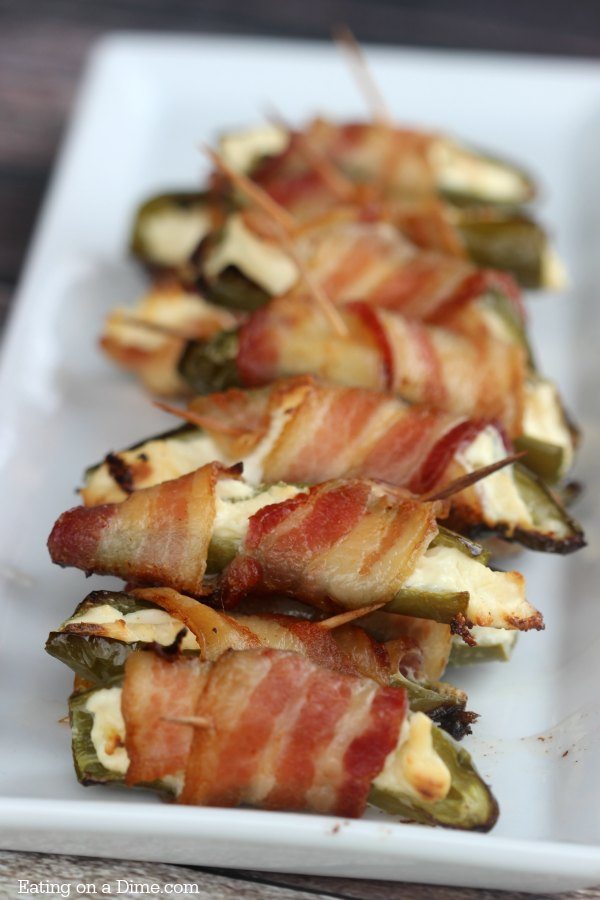 You have to try Bacon wrapped jalapeno poppers with only 3 ingredients, peppers, cream cheese and bacon! These grilled bacon wrapped stuffed jalapeño poppers are easy to make and packed with flavor. Bacon wrapped cream cheese jalapeños are the perfect snack or appetizer for the holidays or any party! The entire family loves these bacon wrapped jalapeño peppers. #eatingonadime #appetizers #jalapeñopoppers #easyappetizers 