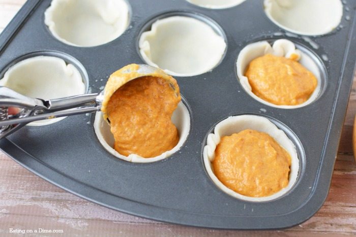 The filling being scooped into the pie crusts in a muffin tin 