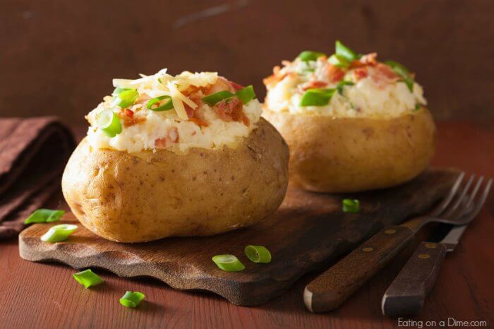 Close up image of two bake potatoes with cheese and chives. 