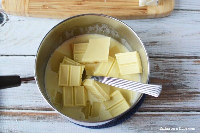 Close up image of white chocolate in a pan in process with a spoon. 