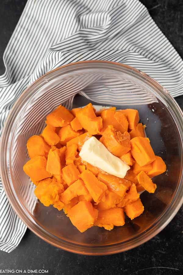 Photo of cooked diced sweet potatoes and butter in bowl.
