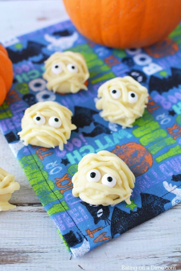 Close up image of Mummy White Chocolate Truffles on a Halloween table cloth. 