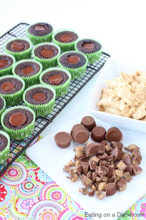 Close up image of cupcakes on a cooling rack with chopped up peanut butter cups on the side. 