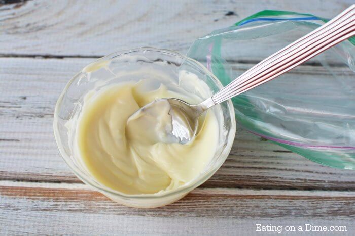 Close up image of a bowl of melted white chocolate with a spoon.