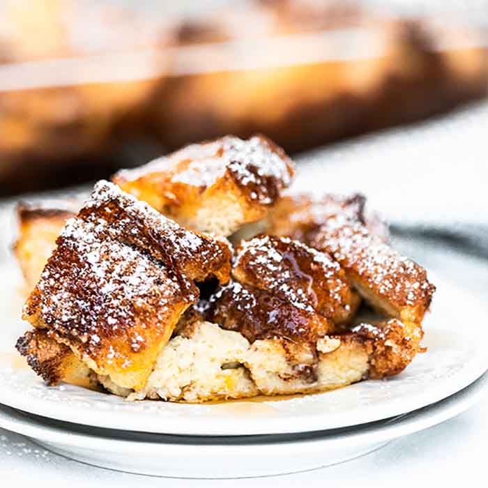 French toast casserole recipe is a delicious overnight breakfast casserole. This recipe is simple enough for busy mornings but perfect for guests. Close up image of french toast casserole on a white plate.