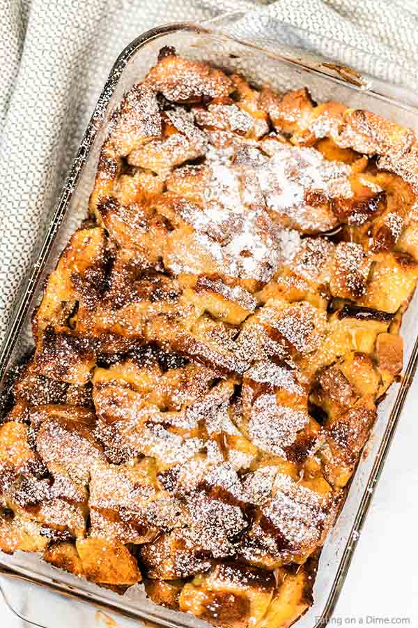 Close up image of french toast casserole in a 9x13 pan with powdered sugar sprinkled on top. 
