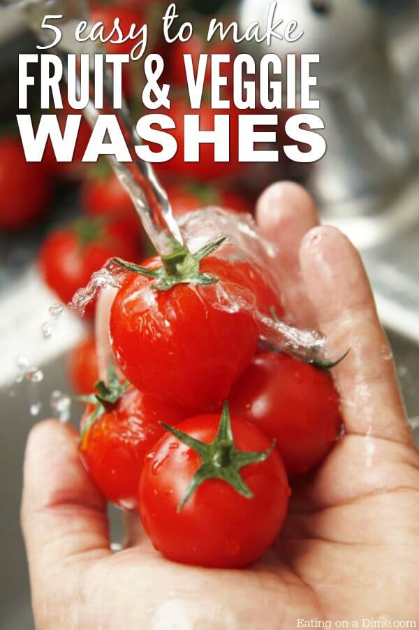 5 small tomatoes in a hand being rinsed by water 