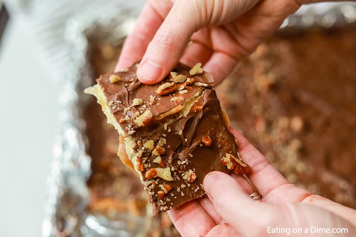Close up image of saltine cracker toffee being broken into pieces. 