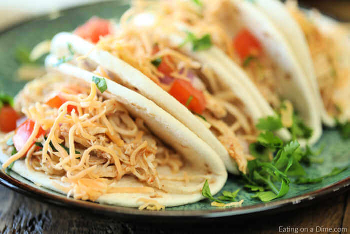 Chicken Tacos on a plate topped with tomatoes, cheese and lettuce