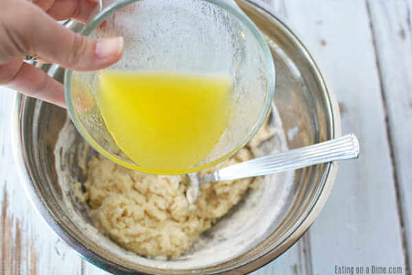 Close up image of melted butter being poured in the dry ingredients. 