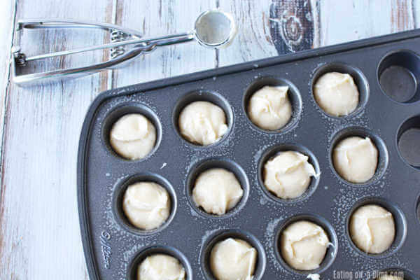 Close up image of mini muffin batter being put in a mini pan. 