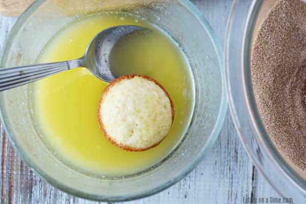 Melted butter in a bowl with a muffin and a bowl of cinnamon and sugar mixture