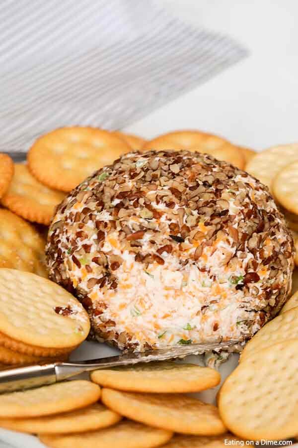 Close up image of cheese ball with a knife and a side of crackers. 