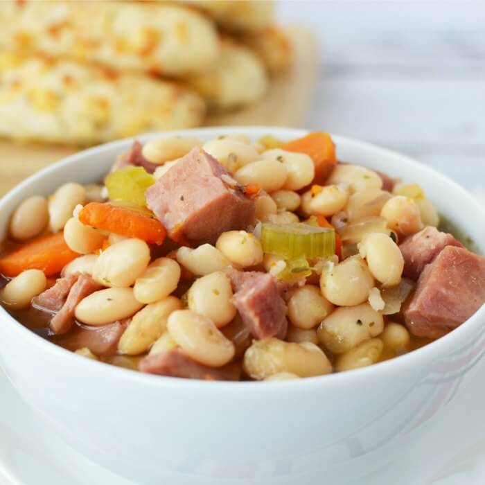 Close up image of ham and bean soup in a white bowl. 