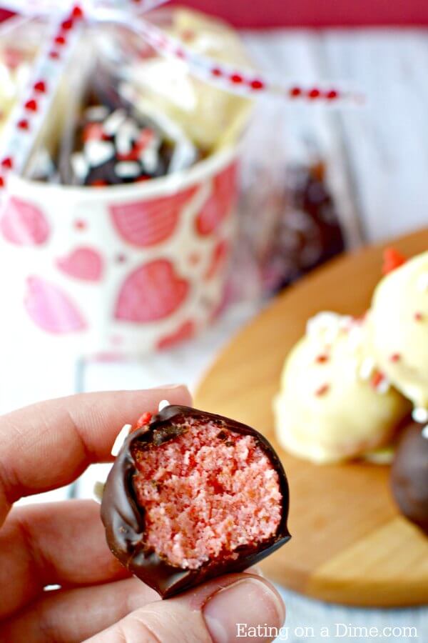 A close up of a Valentine's Day Cake Ball with a bite taken out of it to show the inside of the cake ball. 