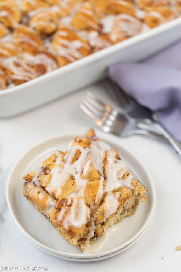 Photo of cinnamon roll french toast casserole with a serving on a white plate. 