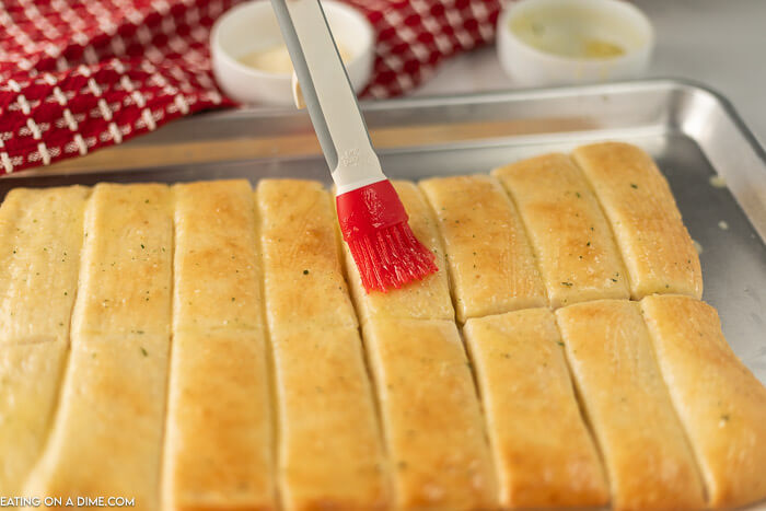 The dough cut into pieces and baked and a basting brush rubbing garlic butter onto the bread sticks.  