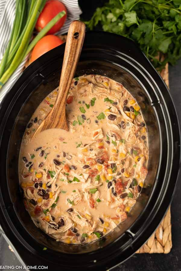 Creamy chicken taco soup in the crock pot with a wooden spoon