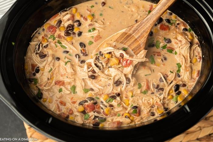 Creamy chicken taco soup in the crock pot with a wooden spoon