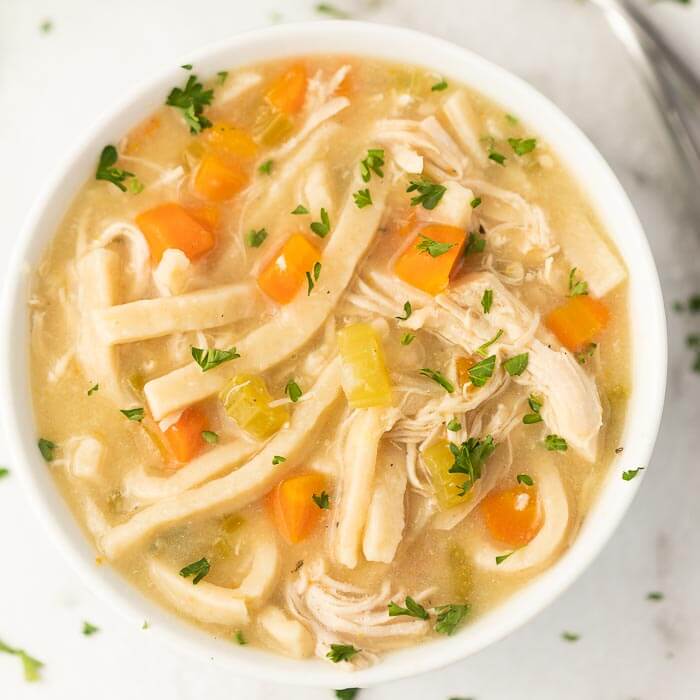 Close up image of chicken noodle soup in a white bowl. 