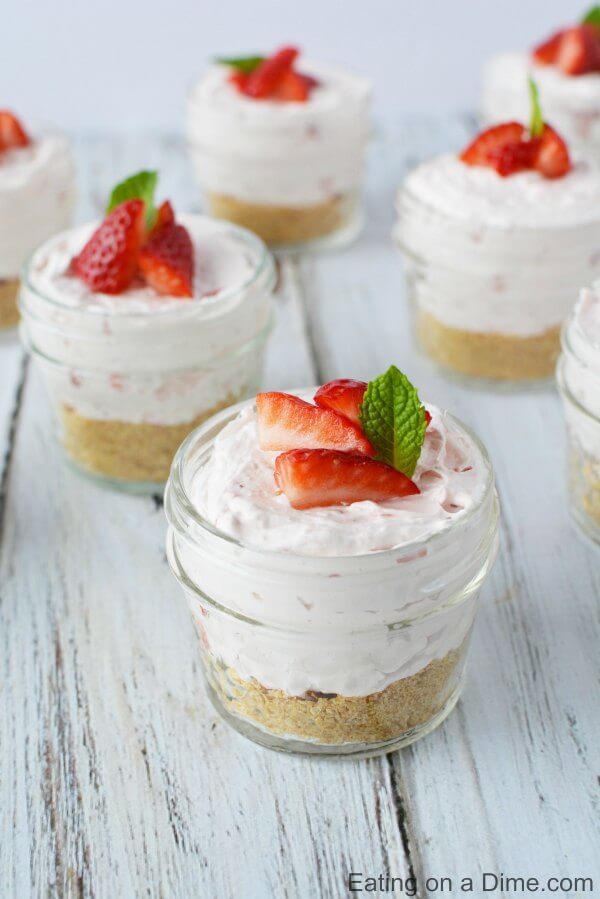 Close up image of cheesecake in a jar topped with strawberries. 