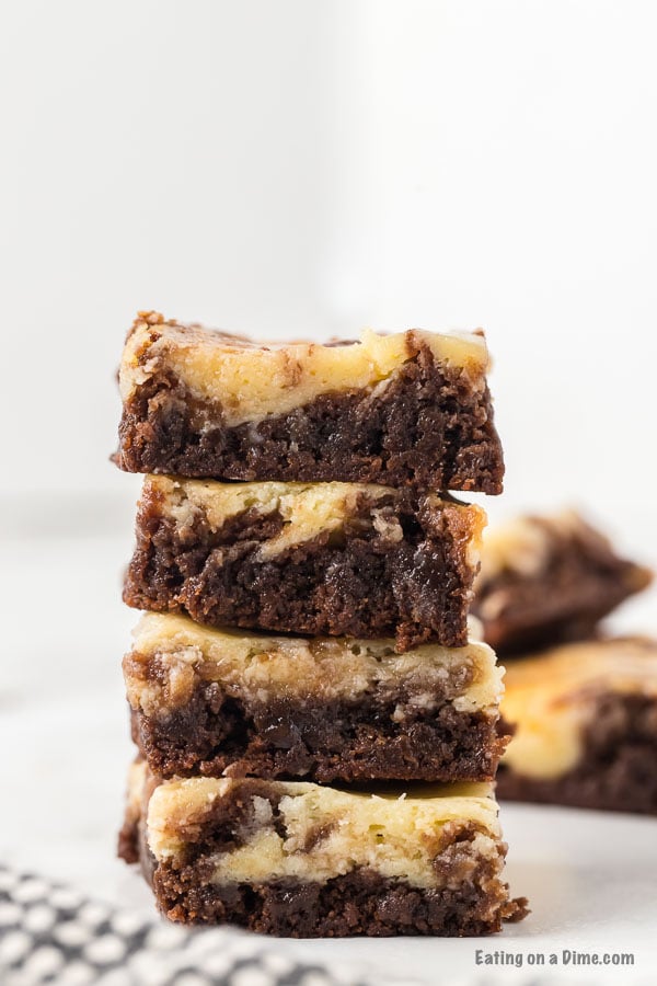 Close up image of squares of cheesecake brownie stacked.