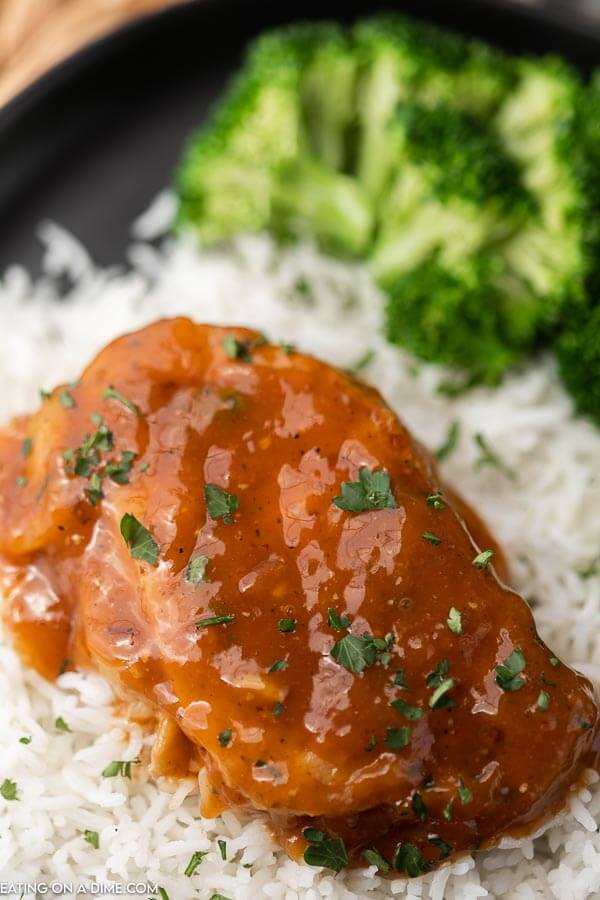 A BBQ pork chop over white rice topped with fresh parsley with a side of broccoli 